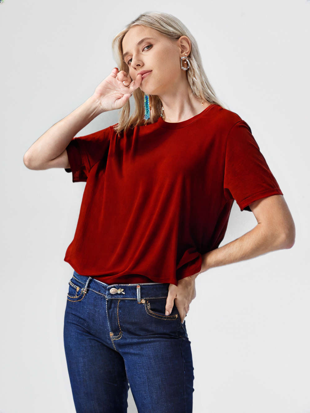 Woman wearing a classic red t-shirt for men styled with blue jeans in a casual pose